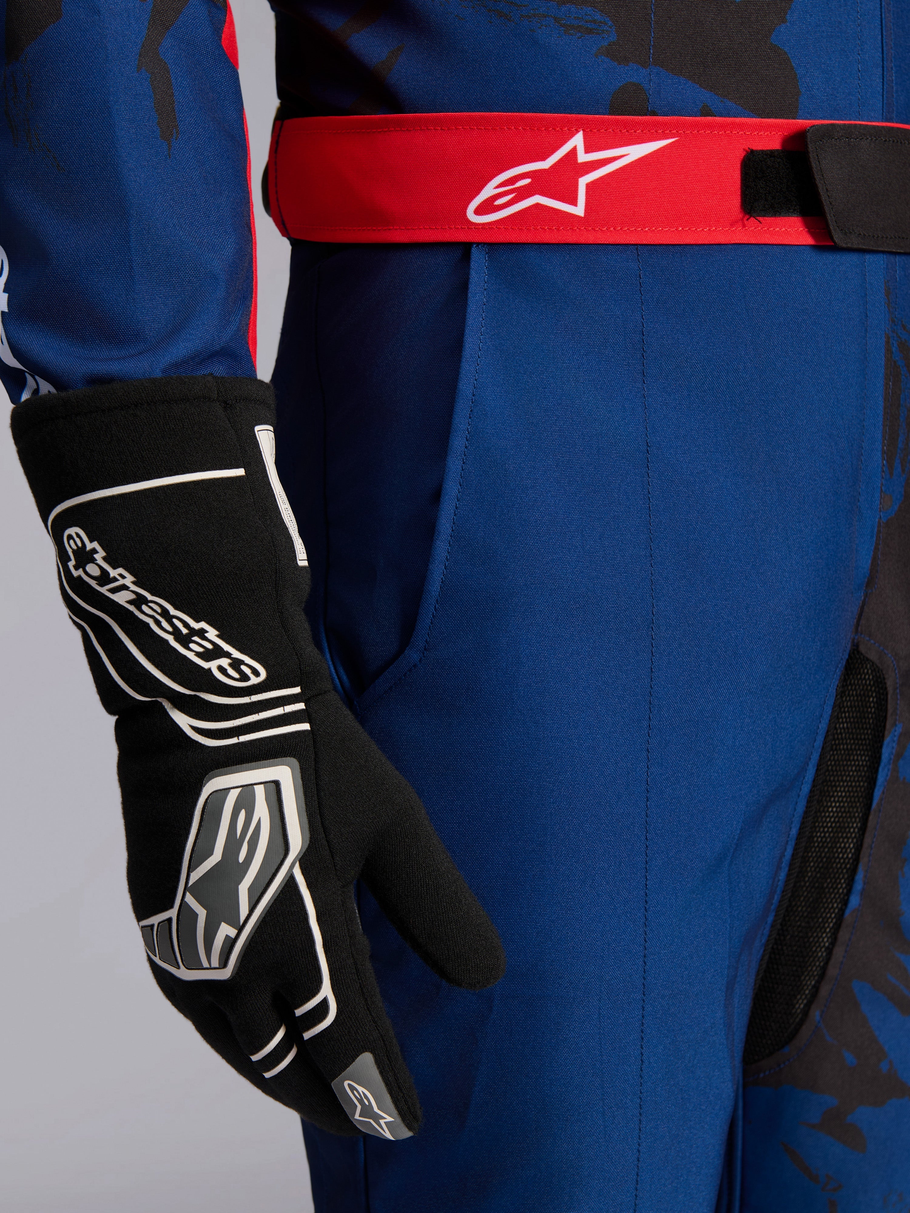 Alpinestars KMX-9 V3 Graphic 5 pak, kartpak, navy en rood, close-up van rode verstelbare tailleband met wit logo, gedragen met zwarte karthandschoen, voorzien van duurzame navy stof en geïntegreerde dijzak