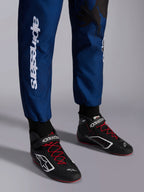 Alpinestars KMX-9 V3 Graphic 5 pak, Navy Rood, close-up van de onderbenen en kartschoenen, marineblauwe stof met witte verticale Alpinestars-branding, zwarte schoenen met rode veters en witte logo's, professionele kartinguitrusting