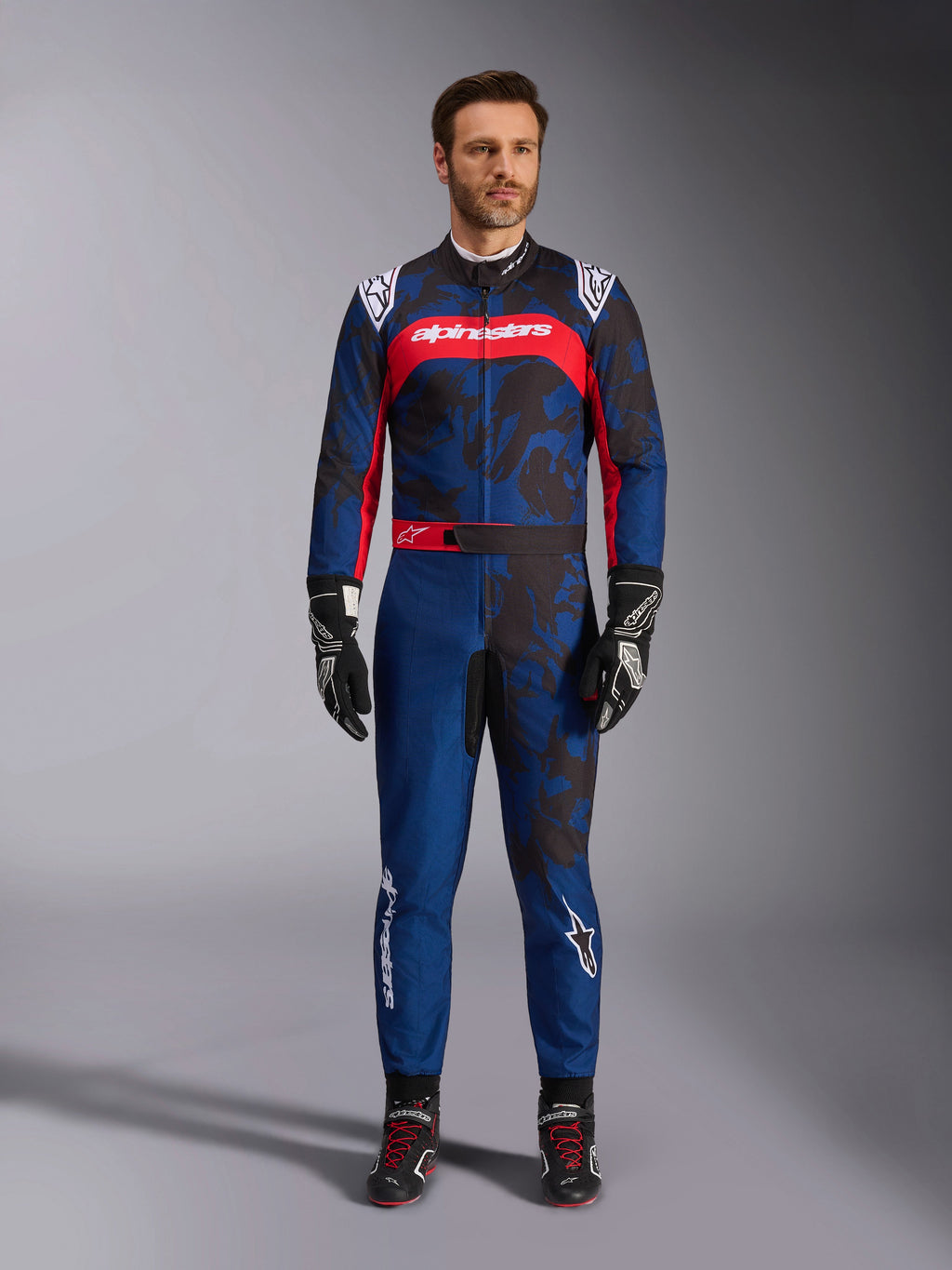 Alpinestars KMX-9 V3 Graphic 5 pak, kartpak in navy en rood, met een abstract grafisch camouflagepatroon, gedragen door een model met zwarte racehandschoenen en schoenen, atletisch ontwerp met opvallende Alpinestars-branding op de borst en benen.
