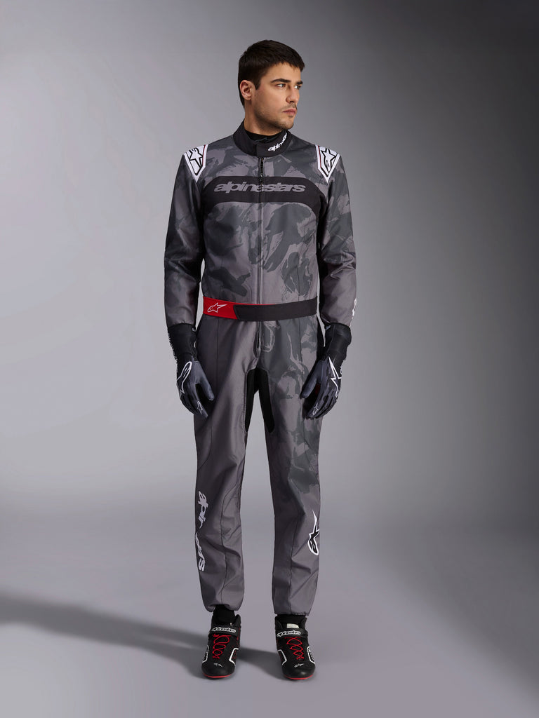 Alpinestars KMX-9 V3 Graphic 5 pak, kartpak, donkergrijs en zwart met camouflage-stijl graphics, voorzien van een zwarte borstband met wit logo en een rood accent op de tailleriem, gedragen met bijpassende racehandschoenen en schoenen, professionele motorsportuitrusting