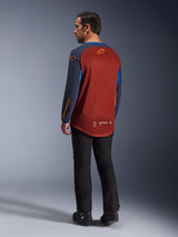 Alpinestars Maxdura Dual Jersey, Rust Brown and Mood Indigo, adventure motorcycle jersey shown from the back, rust-colored mesh panel for ventilation, navy blue sleeves with orange logos, worn with black riding pants and boots, technical off-road gear.