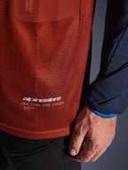 Alpinestars Maxdura Dual Jersey, adventure motorjersey, roestbruin en Mood Indigo, close-up van de mesh torso-stof en donkerblauwe geweven mouw, witte Alpinestars 'One Goal One Vision' branding op de onderste zoom.