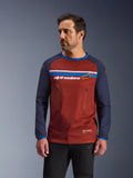Alpinestars Maxdura Dual Jersey, mannelijk model draagt roestbruine en marineblauwe adventure motorjersey, voorzien van dubbele borstzakken met ritssluiting, horizontale borststreep met logo, technische mesh-torso en duurzame geweven mouwen