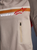 Alpinestars Maxdura Dual Jersey, Aluminum Walnut, detailopname van de mesh torso, horizontale oranje en witte streep met rood logo, verticale borstzak met ritssluiting, adventure motorkleding