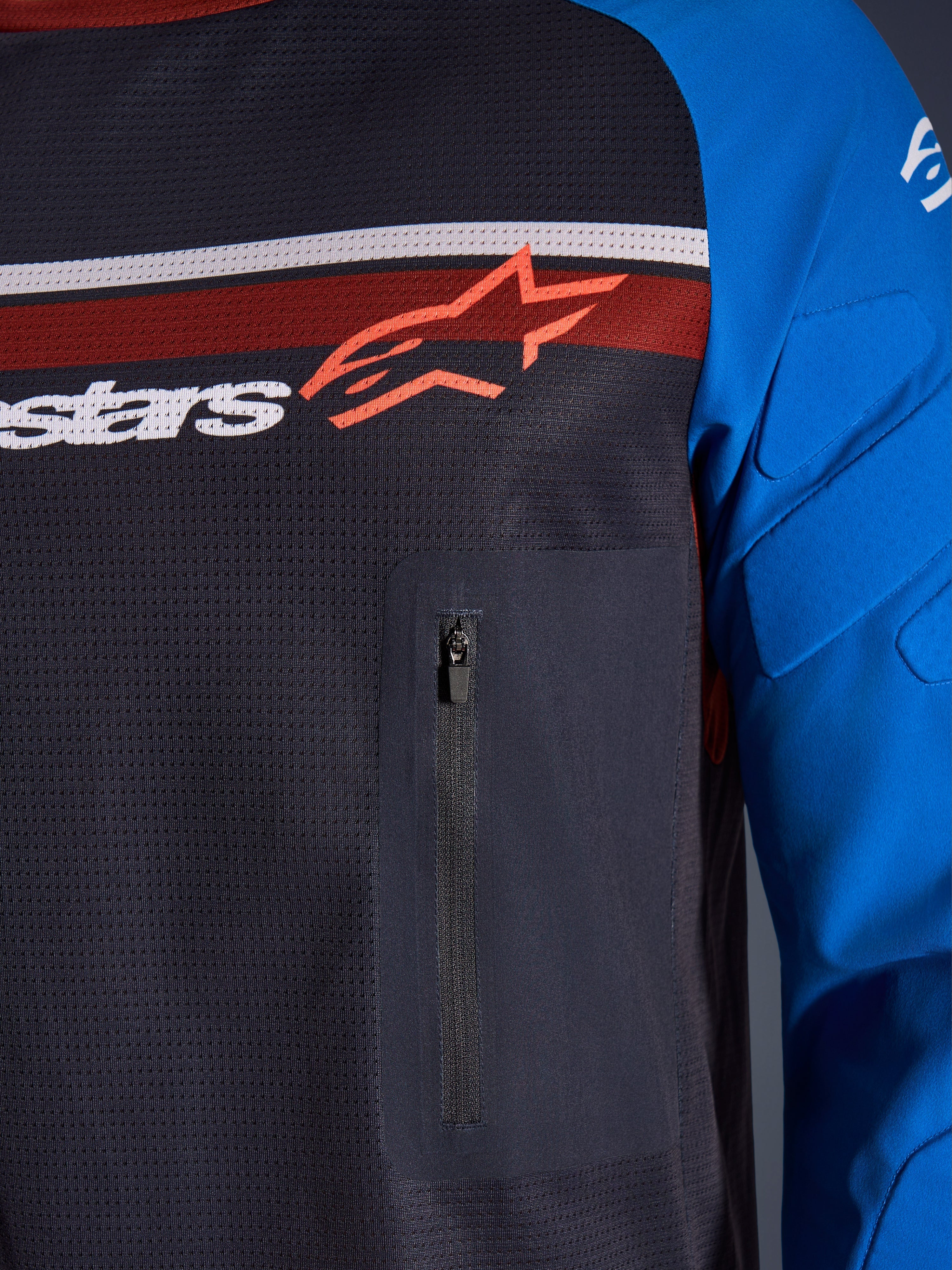 Alpinestars Maxdura Dual Jersey, detailopname van borst en mouw, donkergrijs en koningsblauw, voorzien van een borstzak met ritssluiting, ademende mesh torso en geïntegreerde padding op de mouwen, met het Alpinestars-logo over rode en witte strepen.