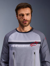 Alpinestars Maxdura Dual Jersey, Mid Gray and Dark Gray, worn by male model, featuring a mesh torso for ventilation, dual zippered chest pockets, white 'alpinestars' branding and red star logo, performance off-road adventure gear