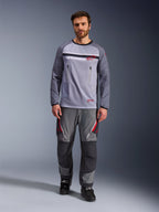 Alpinestars Maxdura Dual Jersey, Mid Gray en Dark Gray, adventure motor jersey met mesh torso en borstzakken met rits, slijtvaste mouwen met geïntegreerde padding, gedragen met bijpassende grijze performance broek met rode accenten, technische off-road motorkleding