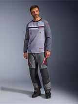 A man wearing the Alpinestars Maxdura Dual Jersey in Mid Gray and Dark Gray, styled with coordinating gray and black adventure pants and black boots, featuring a breathable mesh torso, zippered chest pockets, and red logo accents.