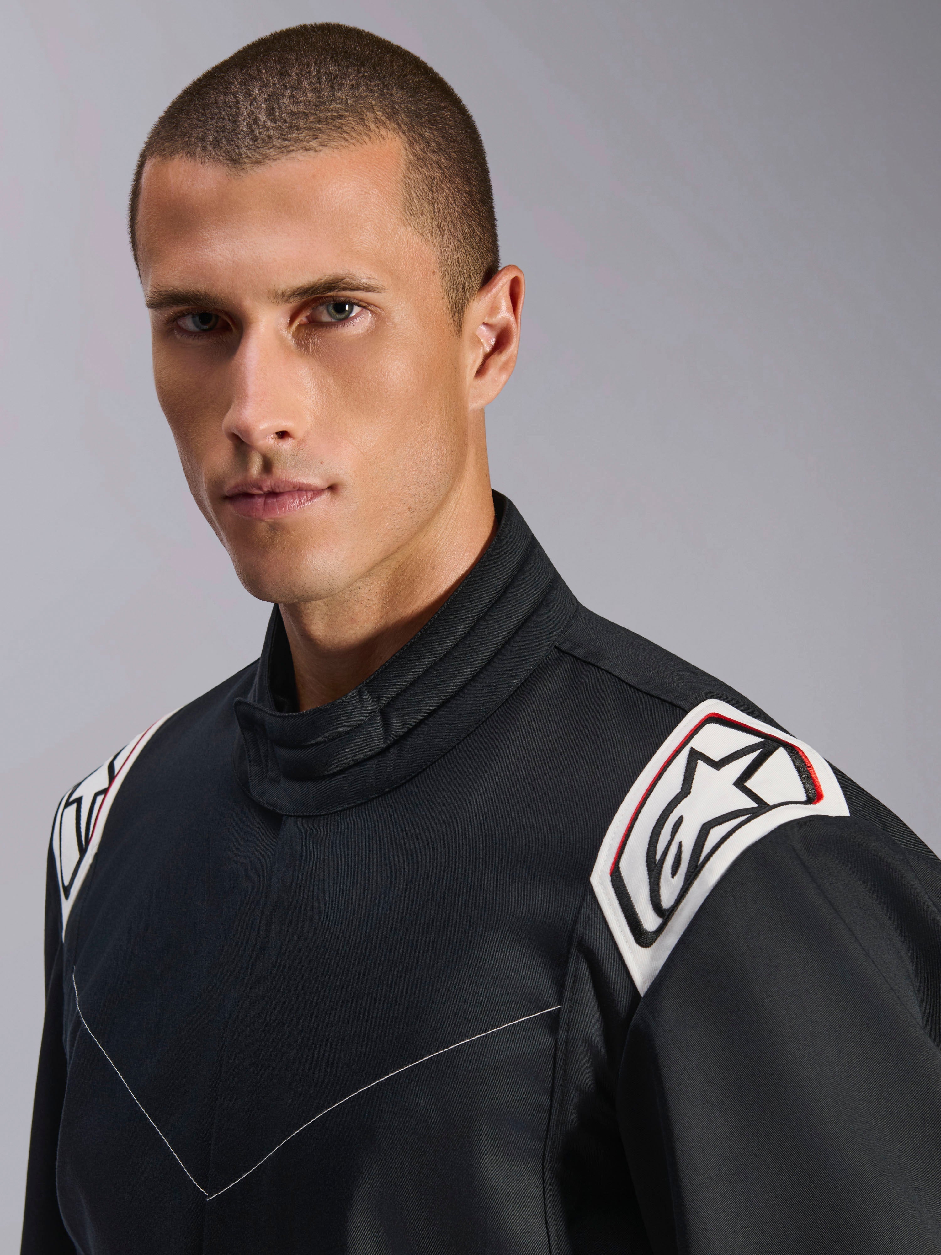 Alpinestars Kart Indoor V2-pak, zwart, close-up van de schouders en kraag, witte schouderepauletten met zwart Astars-logo, ergonomisch kraagontwerp, duurzame poly-katoen keperstof voor indoor karting