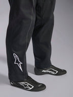 Alpinestars Kart Indoor V2 Pak, zwart kartingpak, close-up van de onderbenen en voeten met een wit Alpinestars-logo op de kuit, gedragen met bijpassende zwart-witte raceschoenen, ontworpen voor recreatief karten