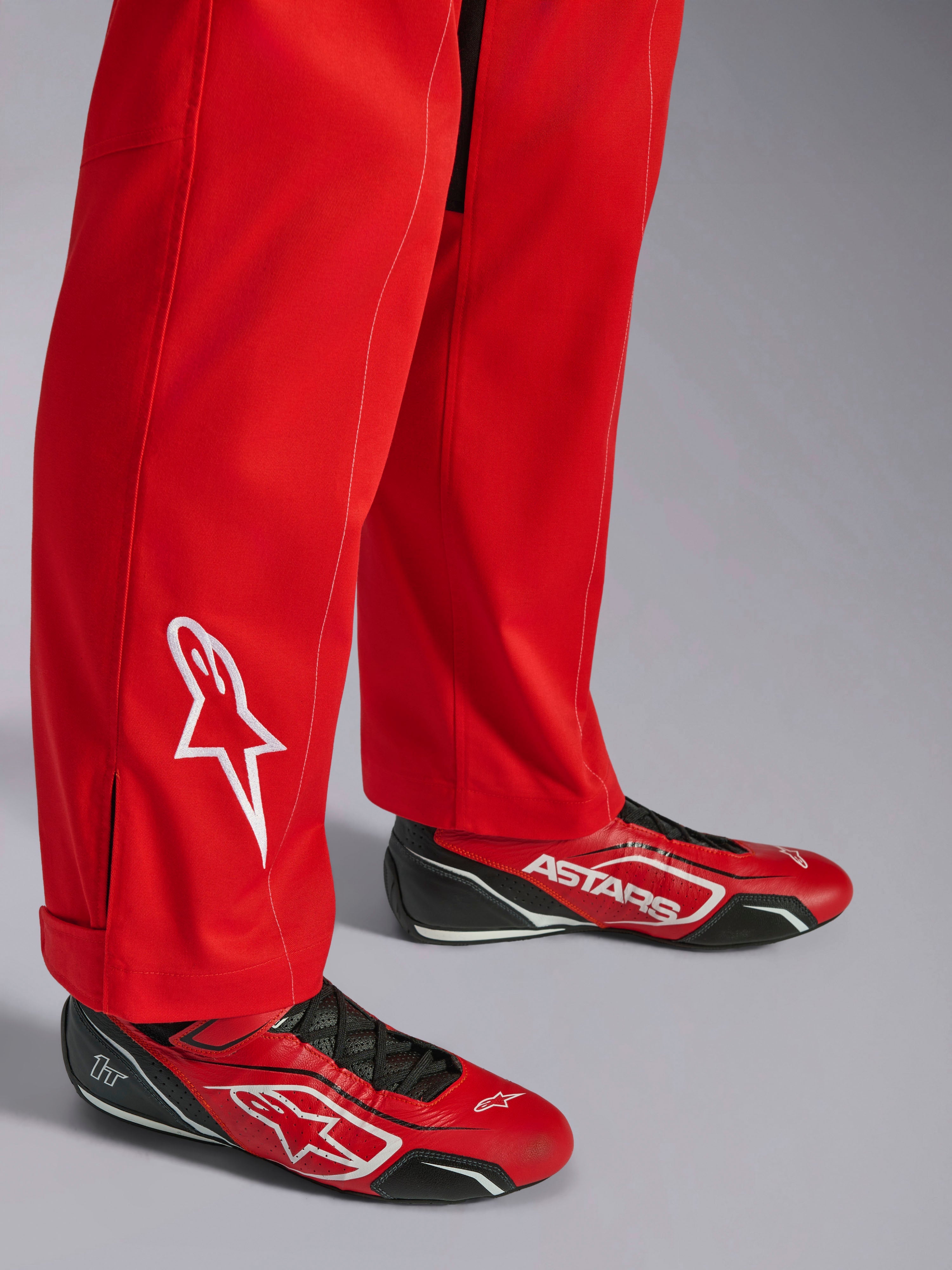 Alpinestars Kart Indoor V2 Pak, rood, detail van het onderbeen met wit geborduurd sterlogo, gedragen met bijpassende rood-zwarte kartingschoenen, enkellaags poly-katoen keperstof materiaal voor recreatief racen