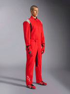 Alpinestars Kart Indoor V2 Suit, rood kartingpak, gedragen door een model met bijpassende rode en zwarte handschoenen en schoenen, met witte logo's op de schouders en het onderbeen, zwarte accenten, ontworpen voor recreatief karten en indoorbanen