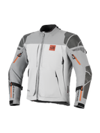Alpinestars Nazca 3L GORE-TEX PRO jas, adventure motorjas, donkergrijs en middengrijs met oranje ritsaccenten, voorzien van All Terra-borstlogo, Superfabric-versterkingen op schouders en ellebogen, meerdere ventilatieopeningen met rits, robuust touring-ontwerp