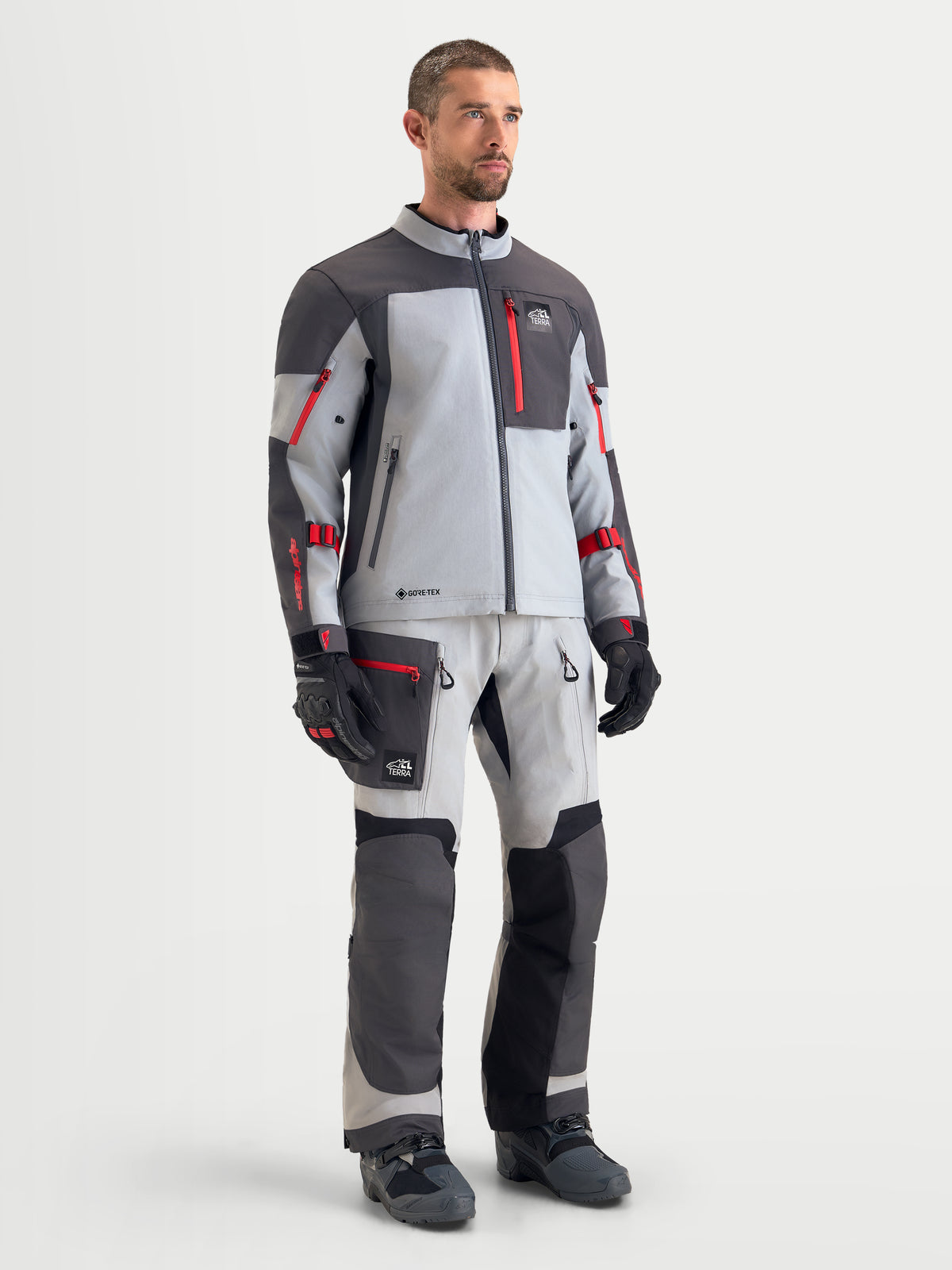 Alpinestars Arenis Gore-Tex uitrustingsset, heren adventure touring motorjas en motorbroek in lichtgrijs en donkergrijs met rode accenten, vooraanzicht op een model met bijpassende waterdichte textiel motorkleding