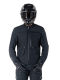 Alpinestars St-7 Prime GORE-TEX jas, zwarte motor touringjas, waterdicht en ademend, ritssluiting aan de voorzijde, meerdere zakken, gedragen met bijpassende helm en handschoenen, premium bescherming voor rijden in alle weersomstandigheden