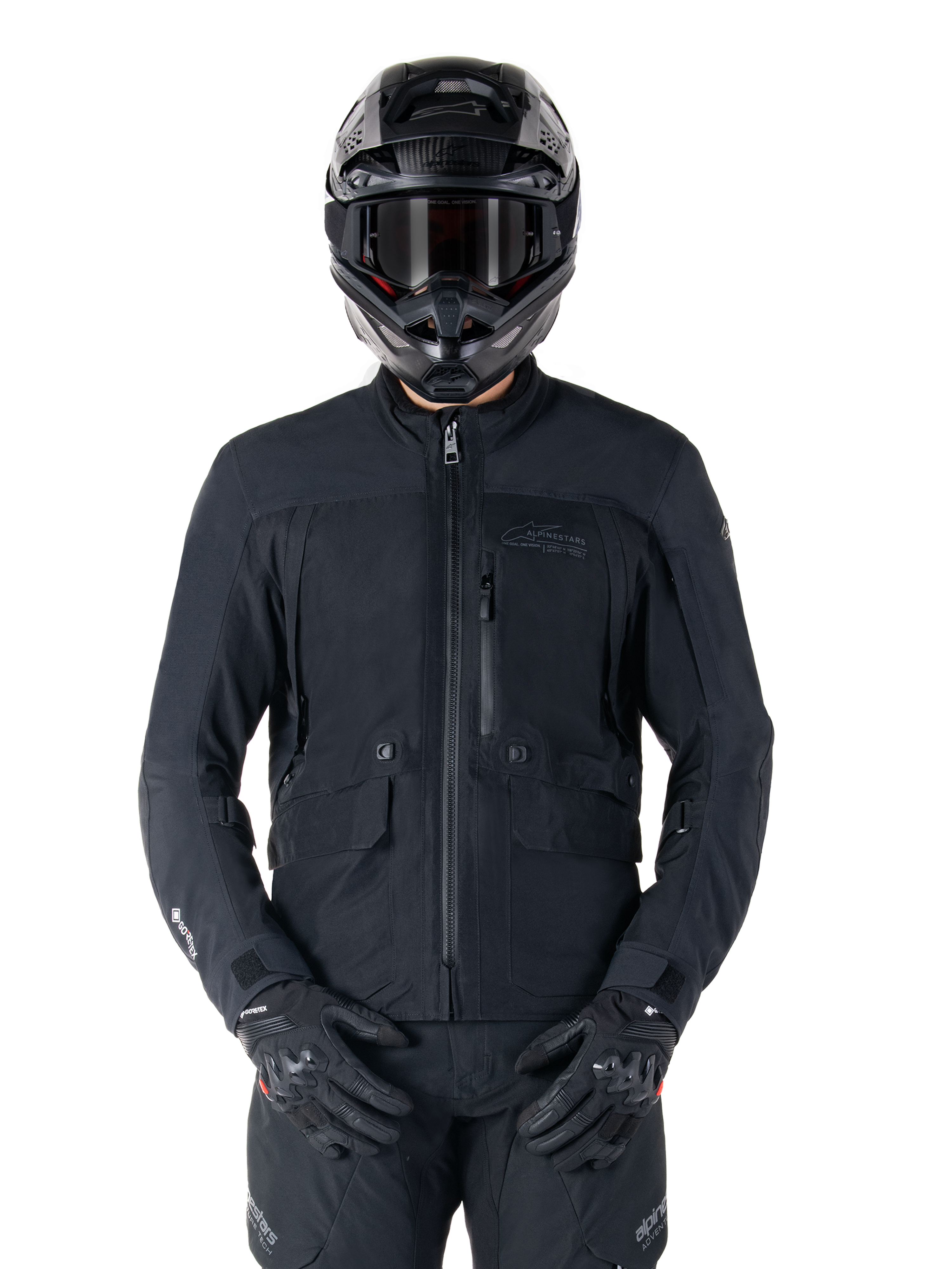 Alpinestars St-7 Prime GORE-TEX jas, zwarte motor touringjas, waterdicht en ademend, ritssluiting aan de voorzijde, meerdere zakken, gedragen met bijpassende helm en handschoenen, premium bescherming voor rijden in alle weersomstandigheden
