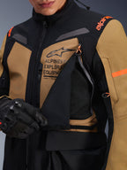 Alpinestars ST-7 2L GORE-TEX jas, adventure touring motorjas, Gobi bruin en zwart, close-up van het open ventilatiepaneel op de borst met ademend mesh, voorzien van Alpinestars Exploration Equipment-branding en oranje accenten.