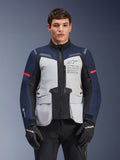 Alpinestars ST-7 2L GORE-TEX jas, motor adventure touringjas, ijsgrijs en donkerblauw met rode accenten, waterdicht en ademend, gedragen door een model met zwarte handschoenen, voorzien van Alpinestars Exploration Equipment-branding op de borst