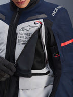 Alpinestars ST-7 2L GORE-TEX Jas, Adventure Touring Jas, Ice Gray, donkerblauw en zwart, detailopname van het geopende ventilatiepaneel op de borst waarbij zwart mesh zichtbaar is, met het Alpinestars Exploration Equipment-logo en rode accent trekkoorden