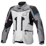 Alpinestars Boulder GORE-TEX Jas, adventure touring motorjas, donkergrijs en ijsgrijs, voorzien van meerdere ventilatieritsen, versterkte schouder- en elleboogpanelen met blauwe en rode accenten, groot Alpinestars-logo op de borst, hoogwaardige waterdichte technische uitrusting