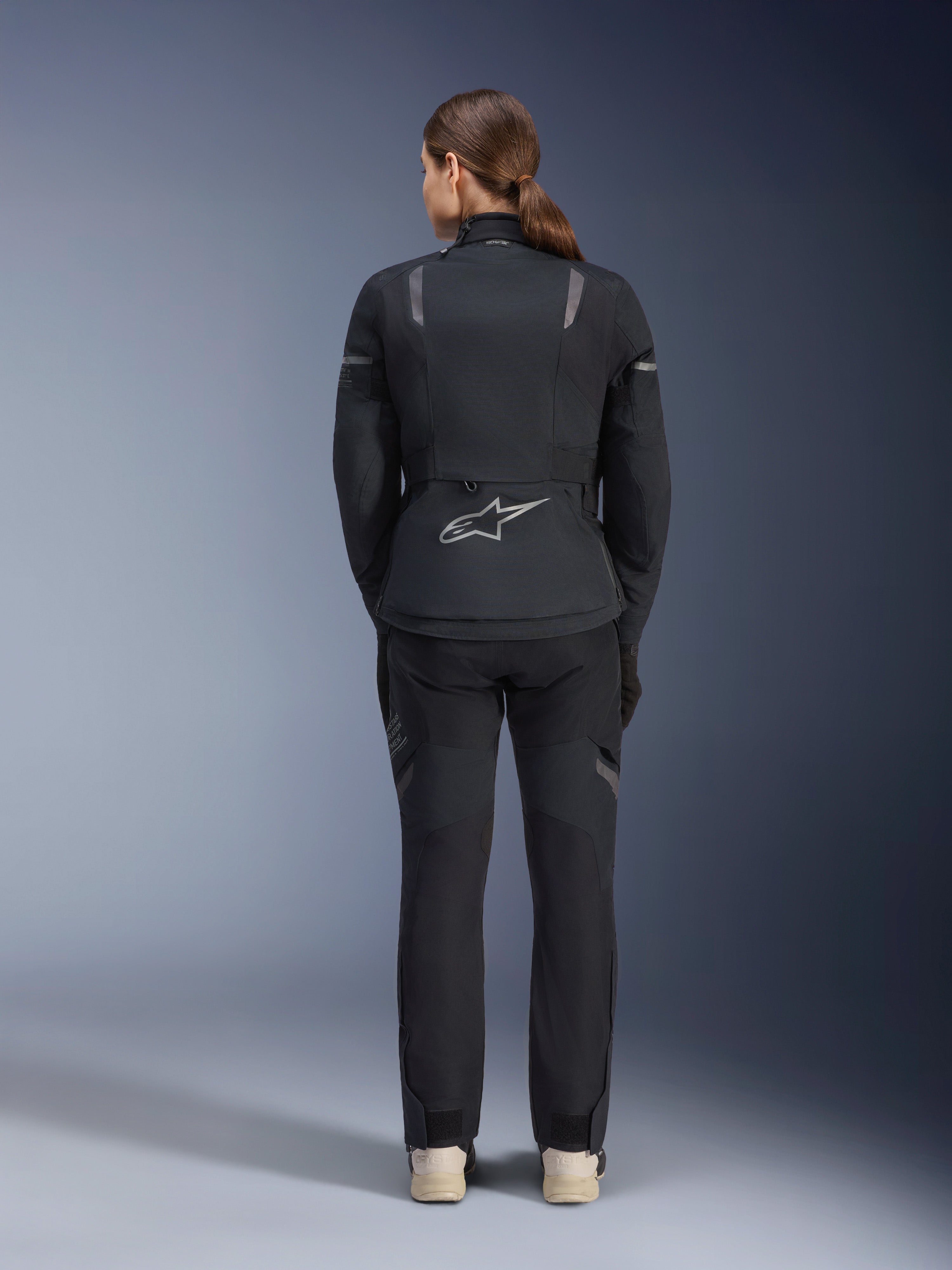 Alpinestars Stella ST-7 2L GORE-TEX jas en broek, adventure touring motoroutfit voor dames, zwart en donkergrijs, achteraanzicht met het Astar-logo en reflecterende details, duurzame waterdichte textielconstructie