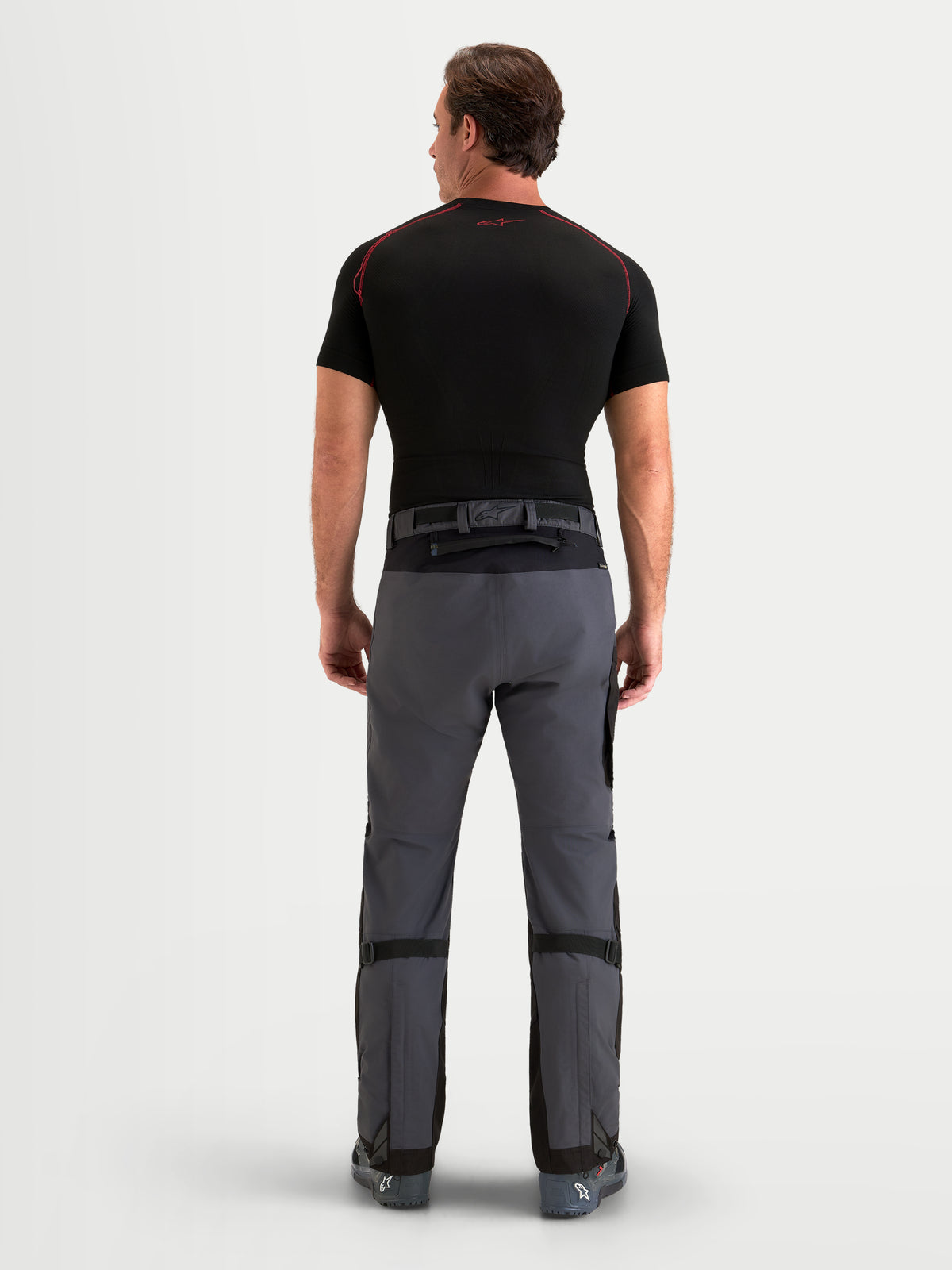 Alpinestars Arenis Gore-Tex Pants, men's adventure touring motorcycle pants in black and deep gray, rear profile view on a model showing waterproof textile construction and waist closure.