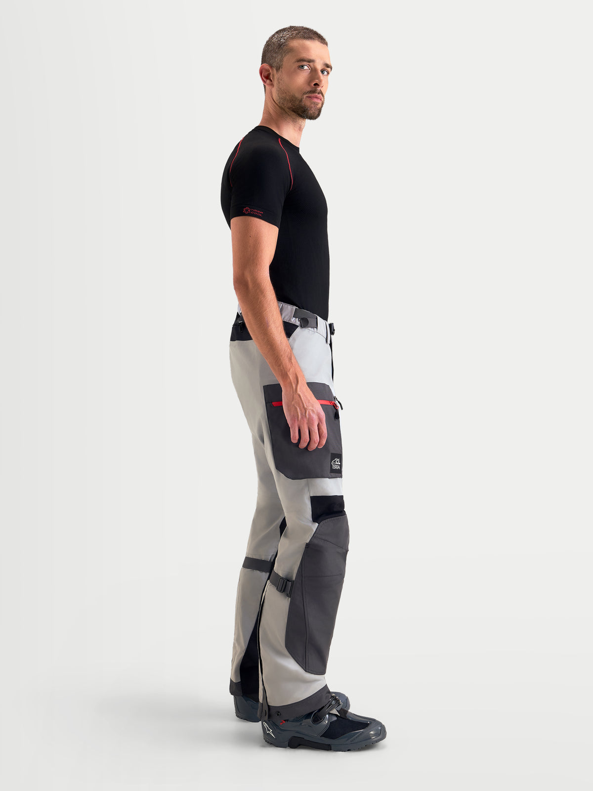 Alpinestars Arenis Gore-Tex Pants, men's adventure touring motorcycle pants in mid gray, deep gray, and black, side profile view showing waterproof textile construction and cargo pocket worn by a model.