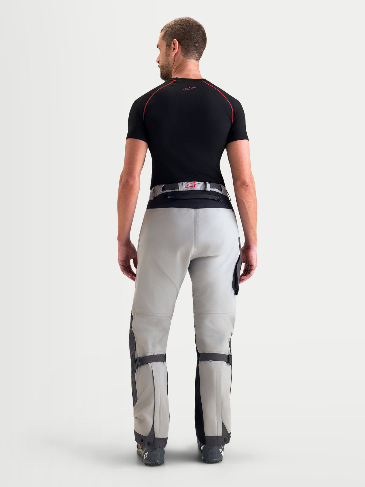 Alpinestars Arenis Gore-Tex® Pants, men's adventure touring motorcycle pants in mid gray, deep gray, and black, rear view on a model showing waterproof textile construction and waist adjustment system.