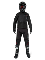 Alpinestars Pro-Dura Jacket, Black Off-Road Enduro Jacket, shown on a model with a complete gear set including a black helmet with red goggles, black pants with red accents, black and white boots, and black gloves, rally-inspired rugged design for trail riding