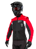 Alpinestars Pro-Dura Jacket, Off-Road Enduro Motorcycle Jacket, Black with Bright Red and White color blocking, worn by a rider with a black helmet and goggles, featuring front zippered pockets and Alpinestars branding, durable textile construction for trail riding