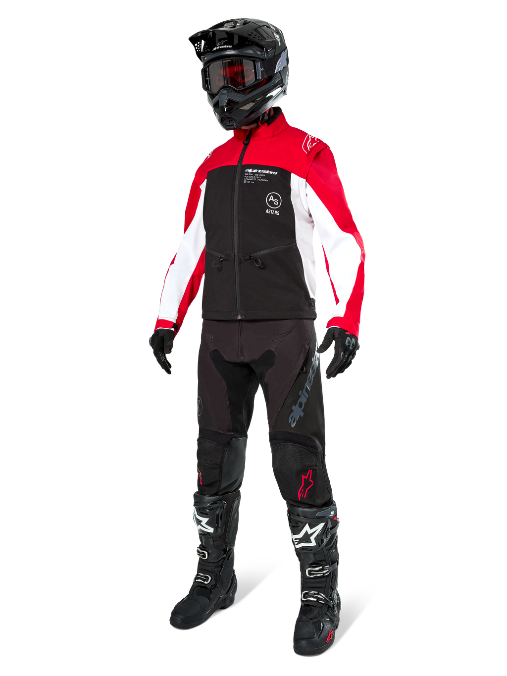 Motorcrossrijder in de Alpinestars Lite-Dura Softshell Jas in zwart, felrood en wit, met een zwart lijf en rood-witte mouwen, gecombineerd met een zwarte broek, een zwarte helm met een rode bril en zwart-witte laarzen, complete off-road race-uitrusting.