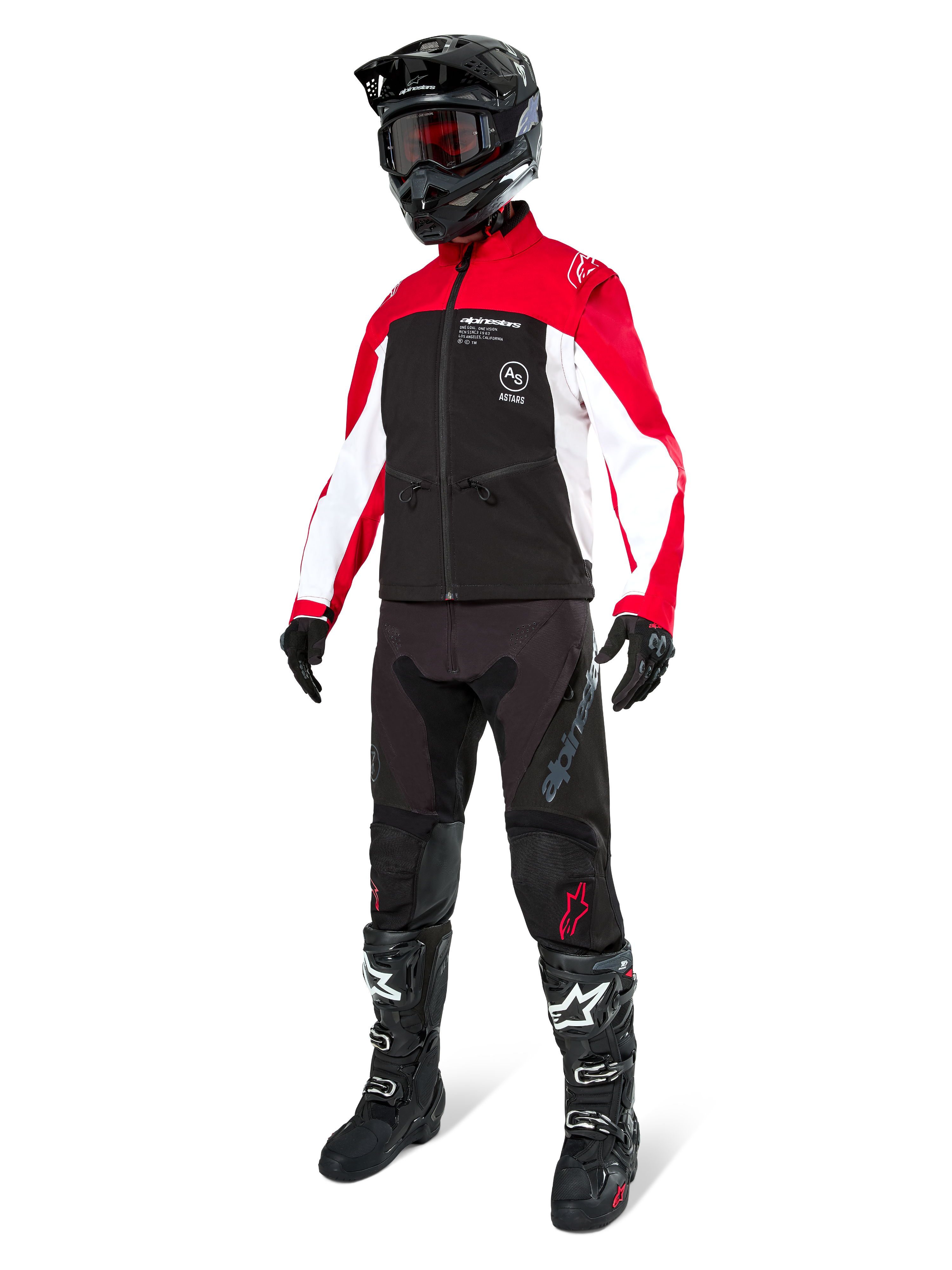 Motorcrossrijder in de Alpinestars Lite-Dura Softshell Jas in zwart, felrood en wit, met een zwart lijf en rood-witte mouwen, gecombineerd met een zwarte broek, een zwarte helm met een rode bril en zwart-witte laarzen, complete off-road race-uitrusting.