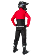 Motorcrosser van achteren gezien in Alpinestars Lite-Dura Softshell Jas, Zwart Felrood en Wit, met een rood bovenpand en een zwart ondergedeelte met witte logo's, gecombineerd met een zwarte broek, zwarte helm en zwarte laarzen, gecoördineerde enduro-outfit voor off-road rijden