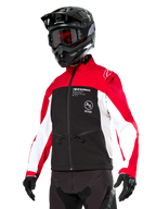 Alpinestars Lite-Dura Softshell Jacket, motorjas, zwart, felrood en wit, gedragen door een rijder met een zwarte motorcrosshelm, rode bril en handschoenen, opvallende branding op de borst, ontworpen voor off-road en enduro rijden
