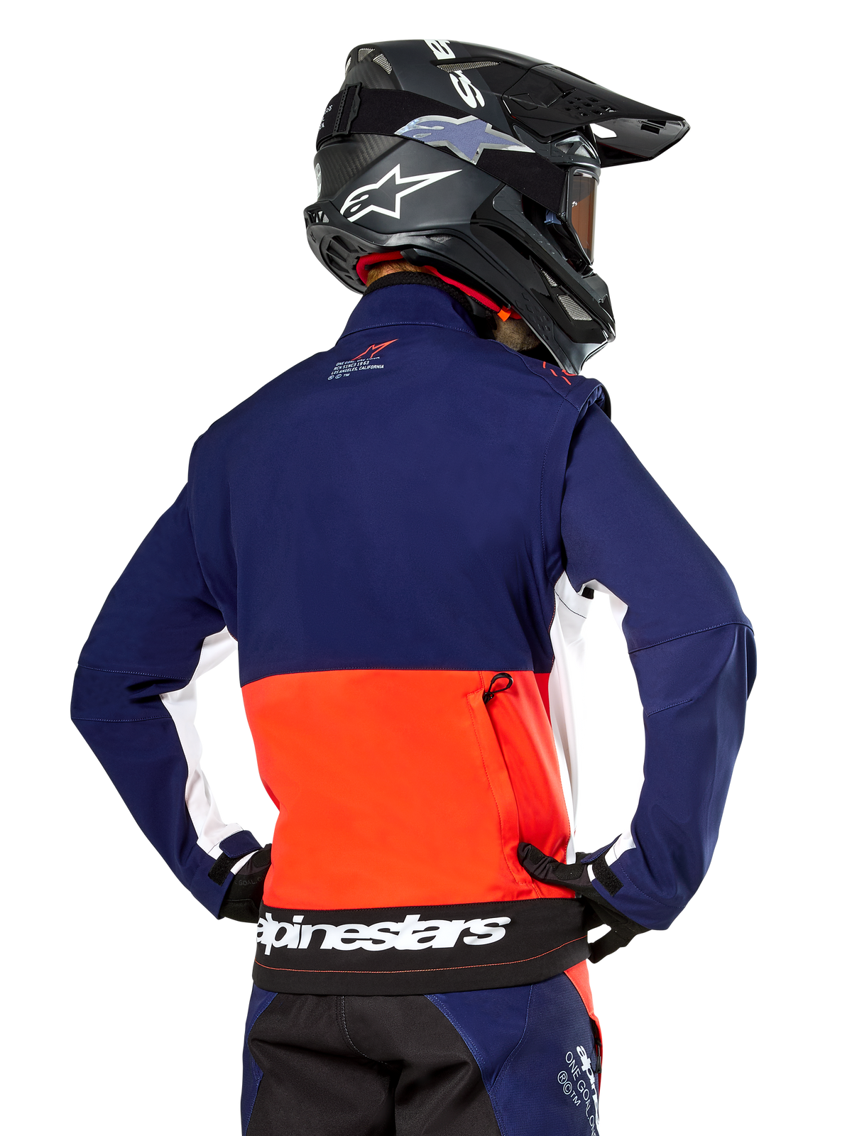 Alpinestars Lite-Dura Softshell Jas, Navy Hot Orange en wit, achteraanzicht gedragen door een motorcrosser, met een groot wit logo op de achterzoom en opbergvak met ritssluiting, onderdeel van een complete off-road race-outfit.