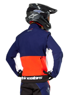 Alpinestars Lite-Dura Softshell Jas, Navy Hot Orange en wit, achteraanzicht gedragen door een motorcrosser, met een groot wit logo op de achterzoom en opbergvak met ritssluiting, onderdeel van een complete off-road race-outfit.