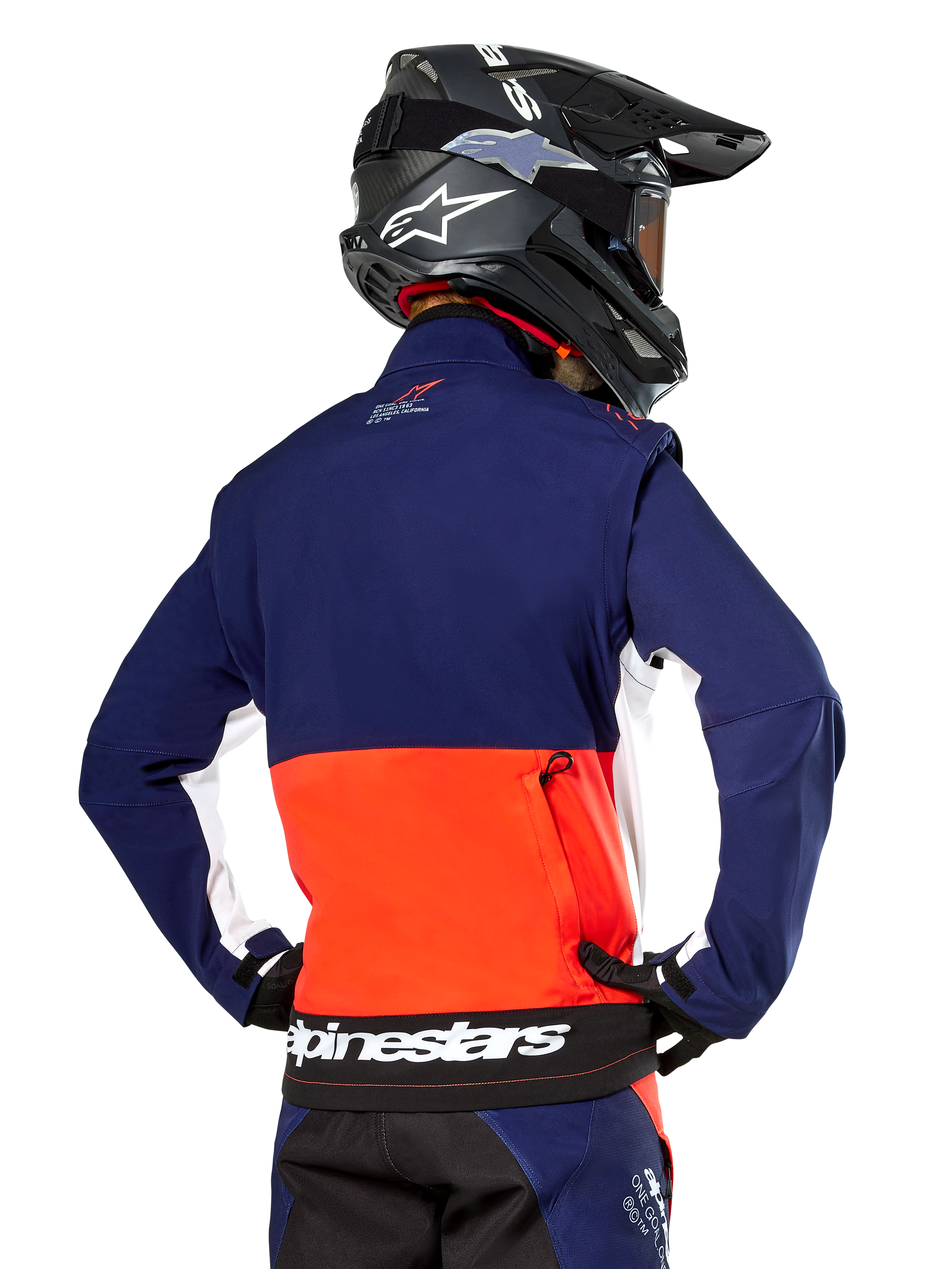 Alpinestars Lite-Dura Softshell Jas, Navy Hot Orange en wit, achteraanzicht gedragen door een motorcrosser, met een groot wit logo op de achterzoom en opbergvak met ritssluiting, onderdeel van een complete off-road race-outfit.