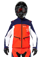 Alpinestars Lite-Dura Softshell Jas in marineblauw, fel oranje en wit, vooraanzicht op een rijder met een zwarte helm en motorbril, technisch kleurgeblokt ontwerp met handzakken met ritssluiting en Alpinestars-branding, veelzijdige kleding voor enduro en off-road rijden
