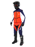 Motorcrossrijder in de Alpinestars Lite-Dura Softshell Jas in Navy Hot Orange en wit, compleet met bijpassende off-road broek, zwarte helm met crossbril en zwarte motorlaarzen, gecoördineerde enduro-uitrustingsset