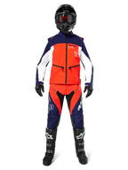 Motocrosser in complete off-road uitrusting, Lite-Dura Softshell Jas in Navy Hot Orange en Wit, bijpassende navy en oranje broek, zwarte helm met crossbril, zwart-witte laarzen en zwarte handschoenen, gecoördineerde outfit voor enduro