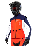 Alpinestars Lite-Dura Softshell Jas in navy, feloranje en wit, motorcross uitrusting, gedragen met zwarte helm en motorbril, beschermende handschoenen en bijpassende racebroek