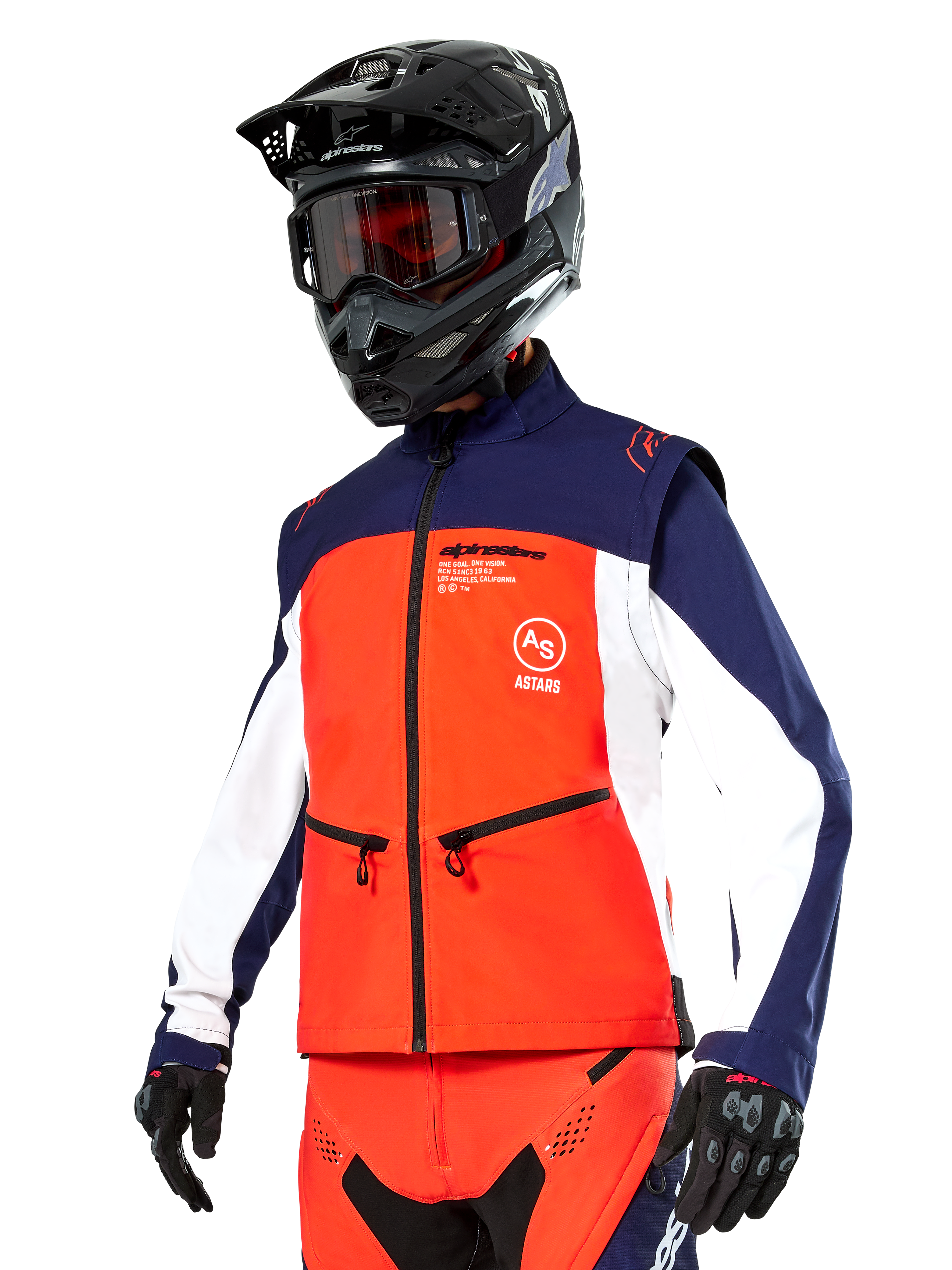 Alpinestars Lite-Dura Softshell Jas in navy, feloranje en wit, motorcross uitrusting, gedragen met zwarte helm en motorbril, beschermende handschoenen en bijpassende racebroek
