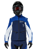 Motocross-rijder met de Alpinestars Lite-Dura Softshell Jas in Navy Bright Blue White, vooraanzicht, gecombineerd met een zwarte helm en een bril met rode glazen, voorzien van een technisch winddicht ontwerp met ritszakken en witte accenten voor off-road enduro rijden