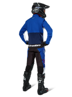 Motocrossrijder van achteren gezien die de Alpinestars Lite-Dura Softshell Jas in Navy Bright Blue en wit draagt, gecombineerd met bijpassende endurobroek, zwarte helm en zwarte laarzen, complete off-road race-uitrusting