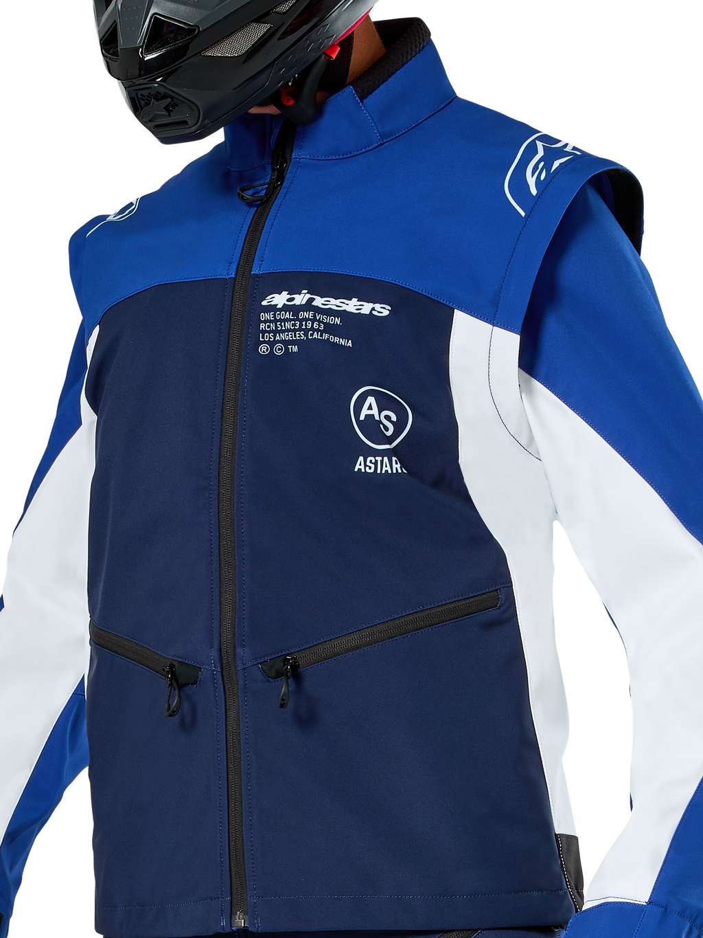 Alpinestars Lite-Dura Softshell Jas, motorcross- en endurojas, marineblauw, helderblauw en wit, met witte Alpinestars-branding op de borst en zakken met rits, gedragen met een zwarte helm, duurzame softshell-constructie met afneembare mouwen voor off-road rijden