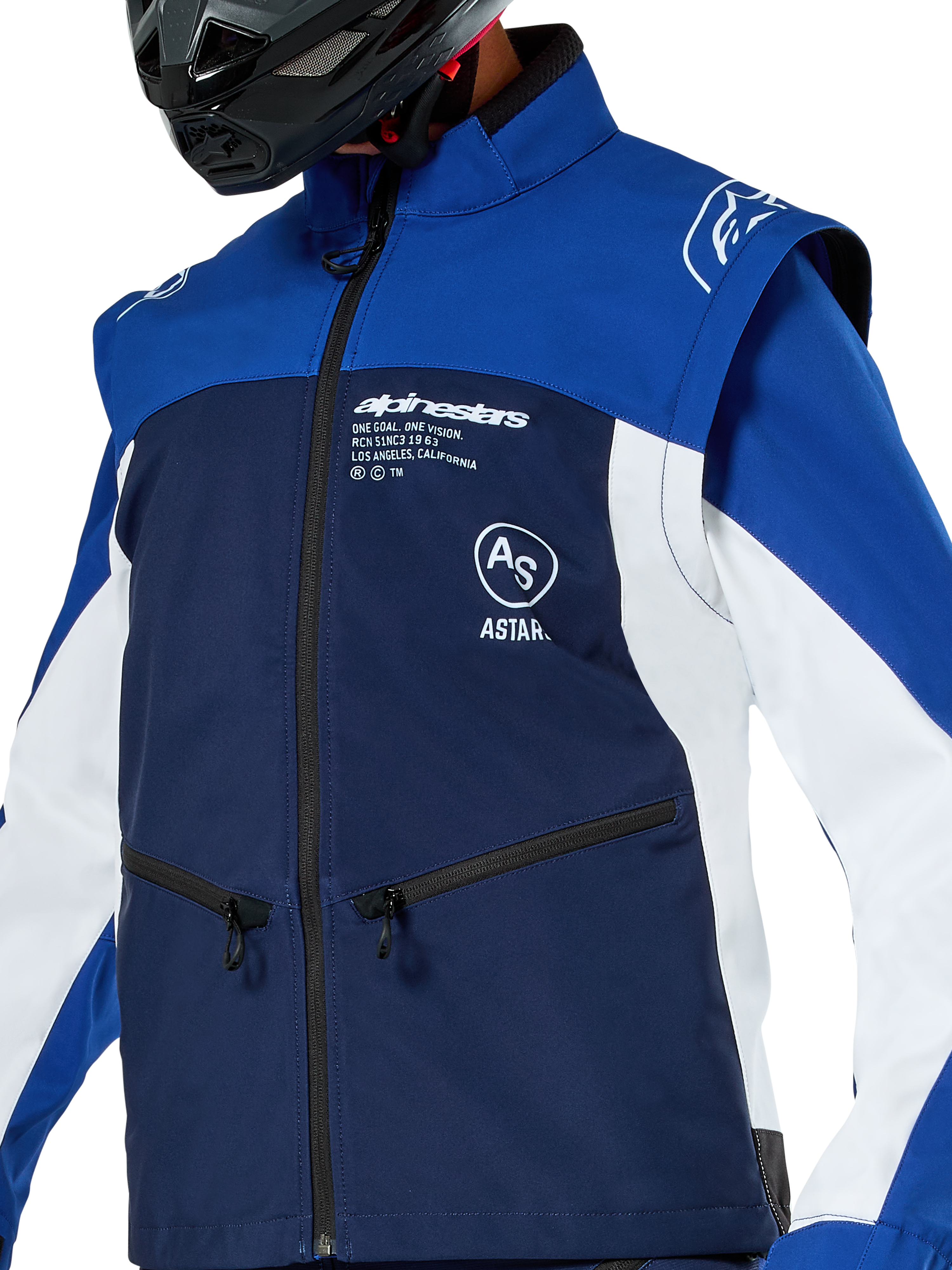 Alpinestars Lite-Dura Softshell Jas, motorcross- en endurojas, marineblauw, helderblauw en wit, met witte Alpinestars-branding op de borst en zakken met rits, gedragen met een zwarte helm, duurzame softshell-constructie met afneembare mouwen voor off-road rijden