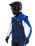 Alpinestars Lite-Dura Softshell Jacket, navy, felblauw en wit, off-road endurojas, gedragen met zwarte helm en rood getinte bril, sportief kleurblokontwerp met meerdere ritsen en merklogo's, duurzaam textiel voor motorcross en trailrijden