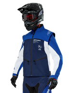 Alpinestars Lite-Dura Softshell Jacket, navy, felblauw en wit, off-road endurojas, gedragen met zwarte helm en rood getinte bril, sportief kleurblokontwerp met meerdere ritsen en merklogo's, duurzaam textiel voor motorcross en trailrijden