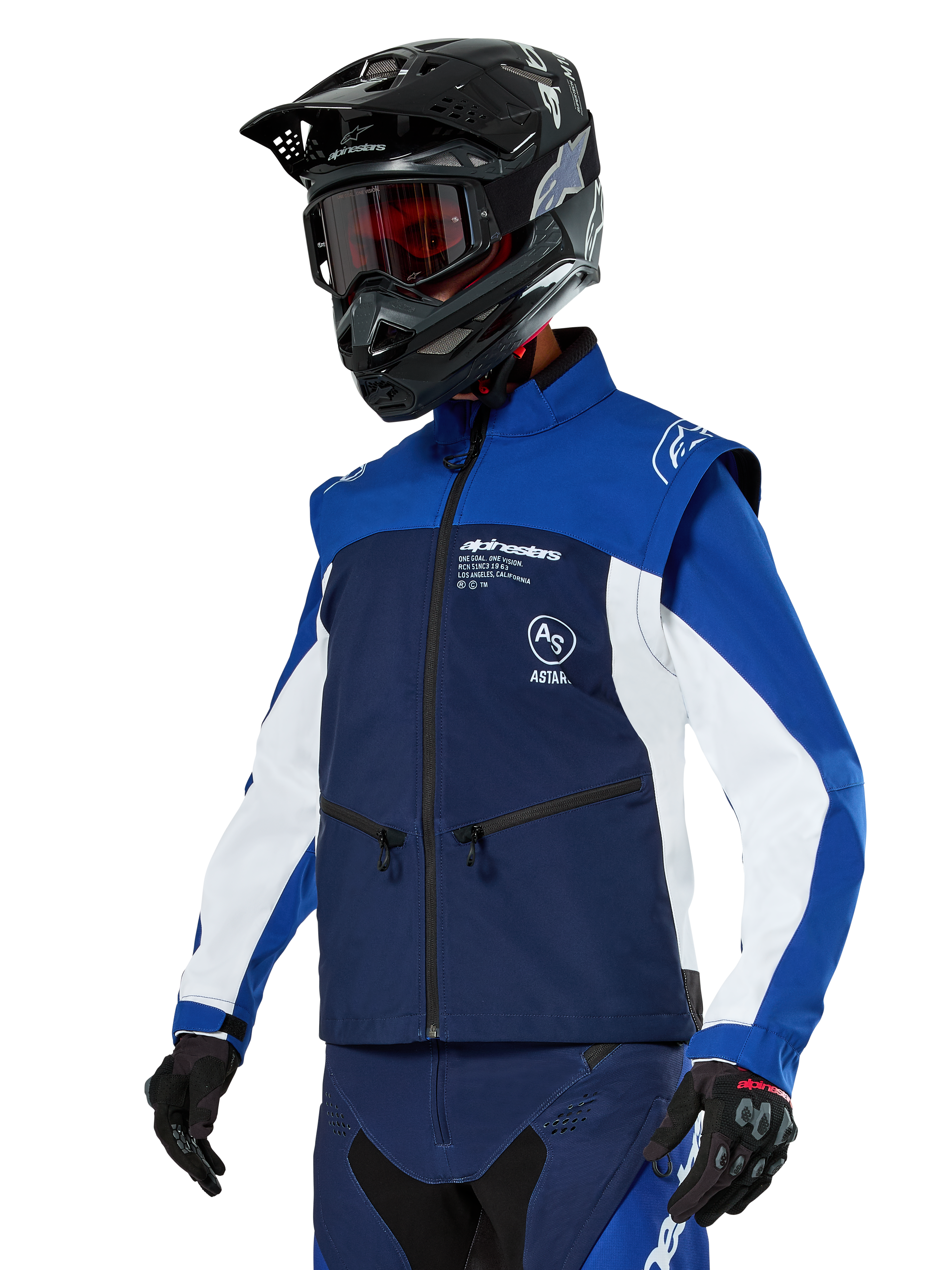 Alpinestars Lite-Dura Softshell Jacket, navy, felblauw en wit, off-road endurojas, gedragen met zwarte helm en rood getinte bril, sportief kleurblokontwerp met meerdere ritsen en merklogo's, duurzaam textiel voor motorcross en trailrijden