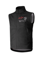 Alpinestars Techstar Softshell Vest, zwart mouwloos motorcrossvest, hoge kraag met rits aan de voorzijde, voorzien van een rood sterlogo met "ASTARS" en "ONE GOAL. ONE VISION." branding op de borst, lichtgewicht winddichte softshell-stof met lichtgrijze binnenvoering, ontworpen voor off-road rijden